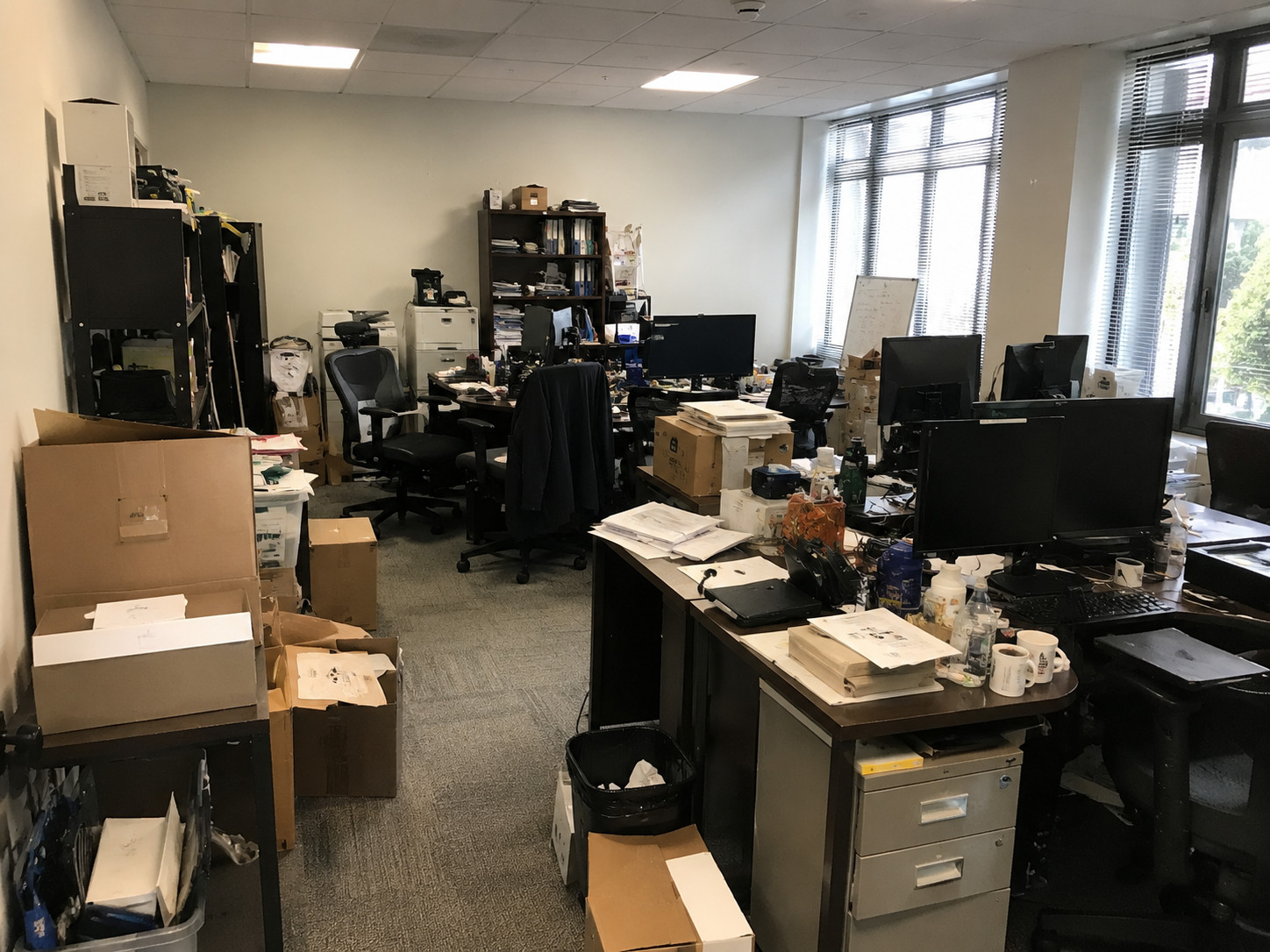 Cluttered Mid-Wilshire office with desks, boxes, papers, and equipment before decluttering service